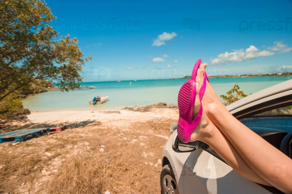 Flip Flops from the window of a car on background tropical beach