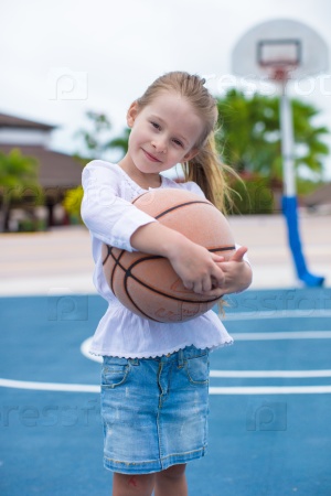 Little girl with basketball on court at tropical resort