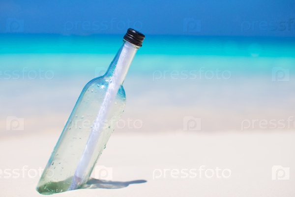Bottle with a message buried in the white sand, stock photo