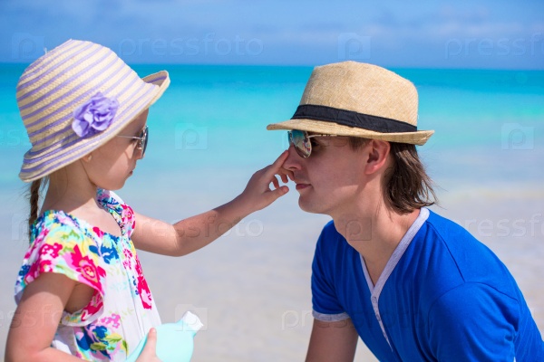 Little girl smearing her dad\'s nose Sun Protection Cream