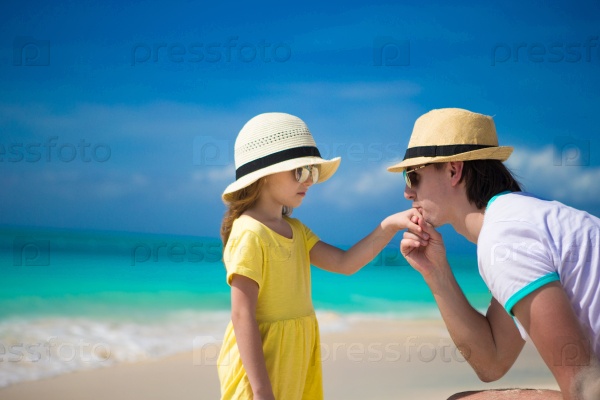 Happy dad kisses the hand of his little daughter on beach
