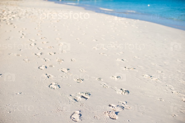 Human footprints on white sand of the Caribbean island