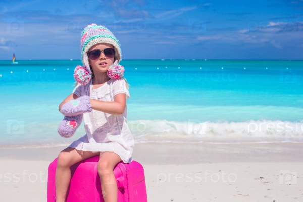 Little adorable girl in winter hat and mittens on summer vacation