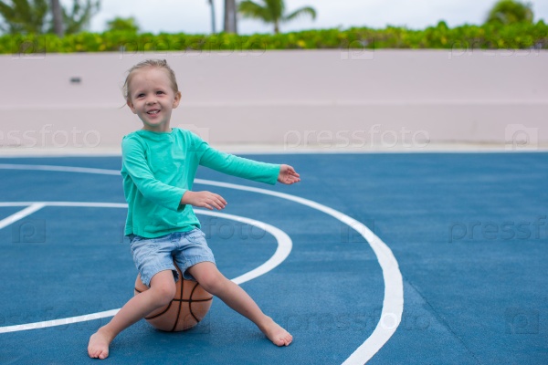 Little girl have fun with basketball on the outdoor court