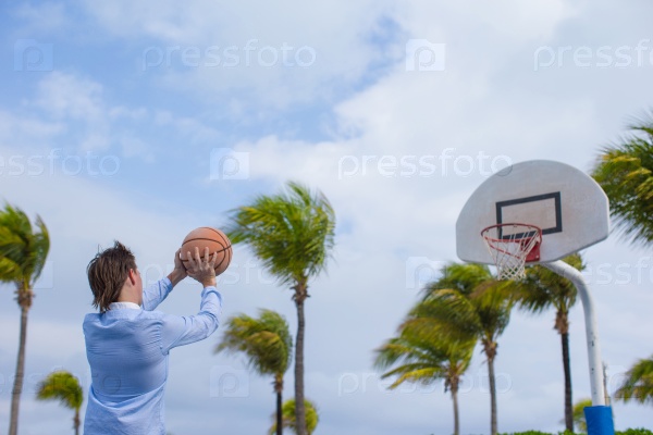 Young man playing basketball outside at exotic resort