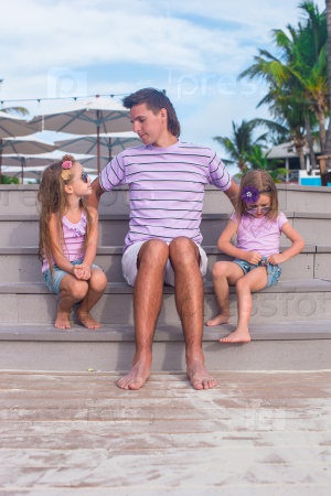 Family of three sitting on beach enjoying ocean view