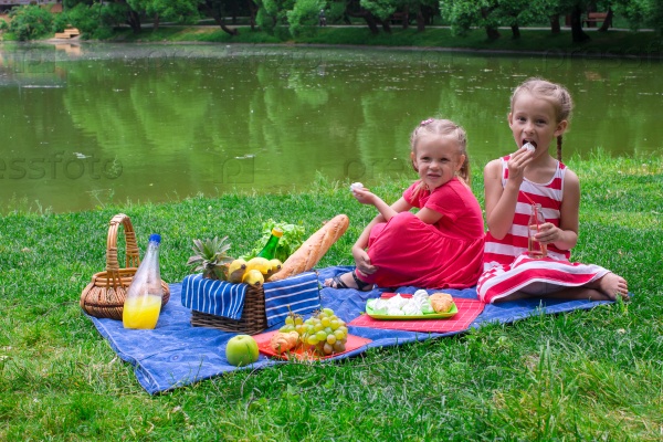 Cute little girls picnicing in the park at sunny day