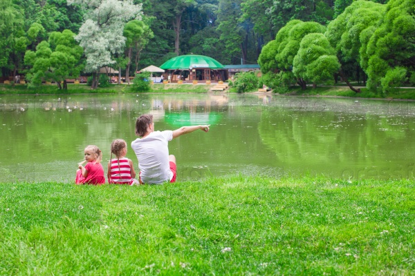 Happy father and little daughers relax near the lake, stock photo