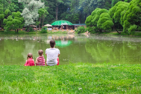 Happy father and little daughers relax by the lake