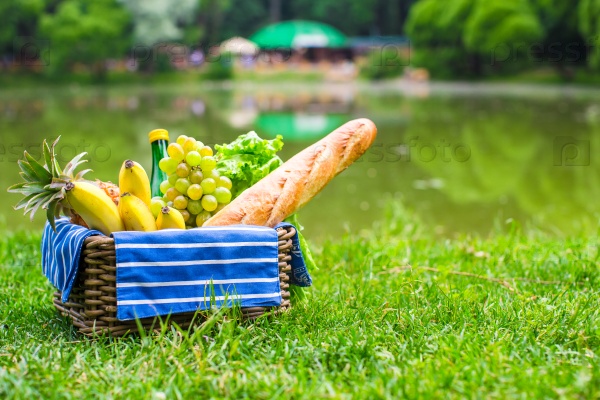 Picnic basket with fruits, bread and bottle of