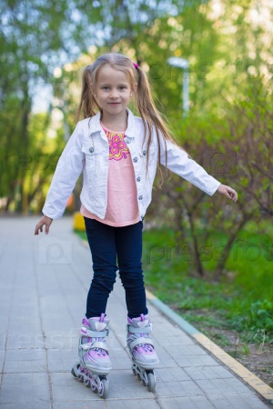 Adorable little girl on roller skates in the park