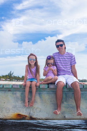Family of three on wooden dock enjoying ocean view