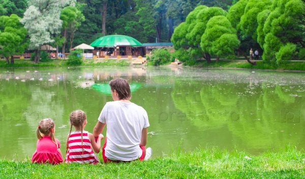Happy father and little daughers relax near the lake, stock photo