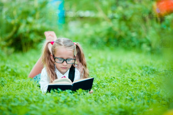 Adorable little school girl with book outdoor. Back to school, stock photo