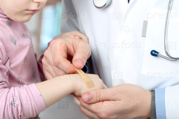 Doctor putting to bab girl plaster on the sore arm