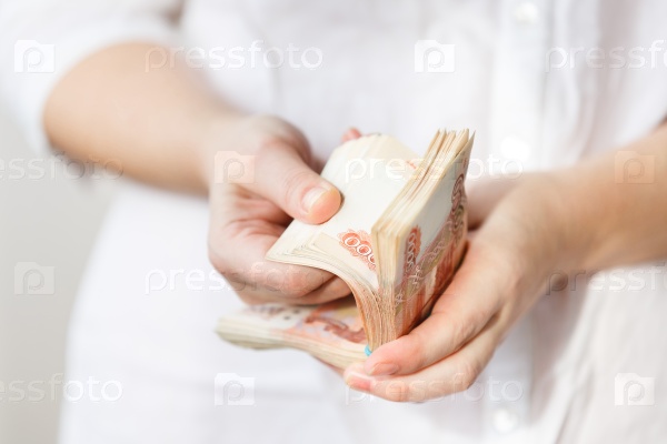 Hand of woman holding five thousand rubles banknotes on the white background, stock photo