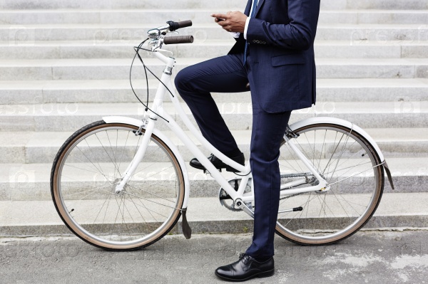 Businessman using his cellphone while going to work on his bicycle, stock photo