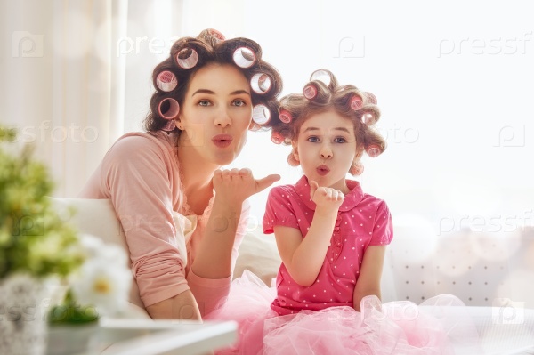 Happy loving family. Mother and daughter are doing hair and having fun. Mother and her child girl playing, kissing and hugging.