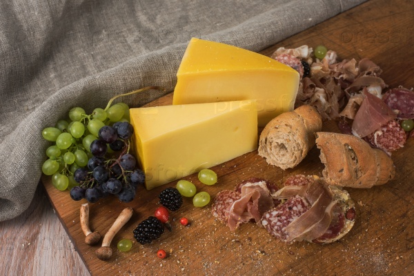 Fresh grapes, cheese bacon berries and salami on wooden table, stock photo