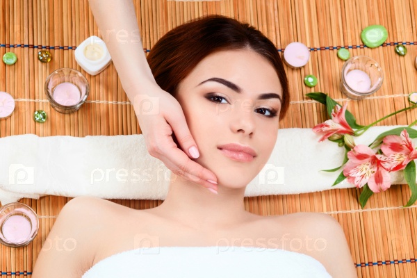 Beautiful young woman at a spa salon resting on a straw mat. Concept of body care and relaxation, stock photo
