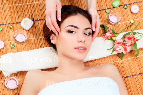 Beautiful young woman at a spa salon resting on a straw mat. Concept of body care and relaxation, stock photo