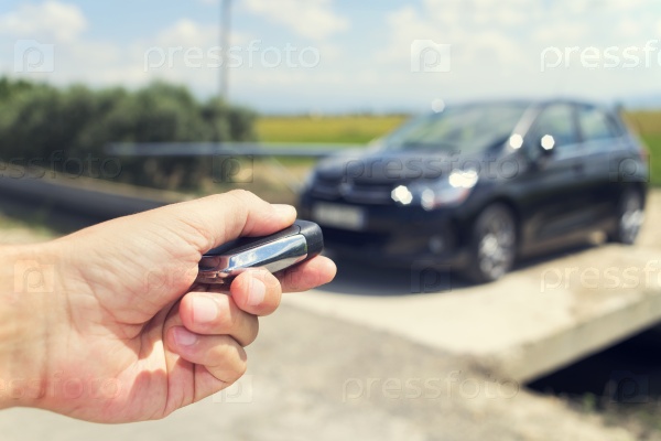 closeup of a young man unlocking the doors of his car with the control remote key, outdoors, with a filter effect