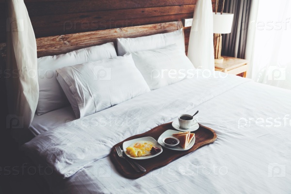 Brekfast on a tray in bed in hotel, white linen, wooden intreior, stock photo