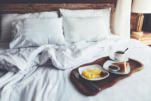 Brekfast on a tray in bed in hotel, white linen, wooden intreior, stock photo
