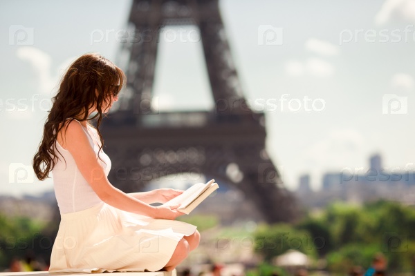 Beautiful woman reading book in Paris background the Eiffel tower, stock photo