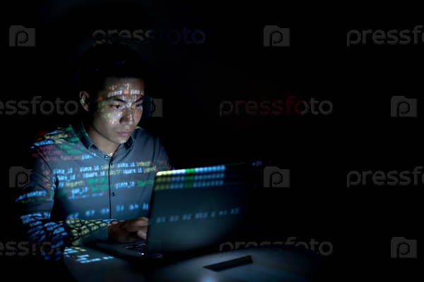 Software developer coding on his laptop at night