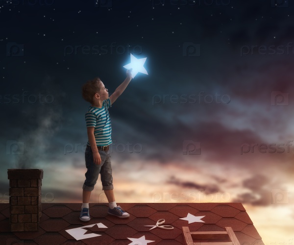 Fairy tale! The child hanging the stars in the sky. Boy on the roof cuts out stars.