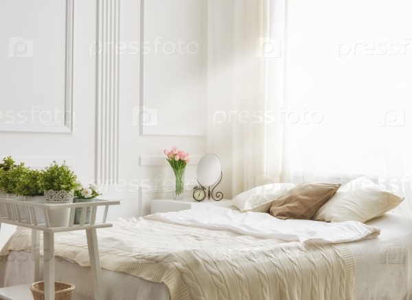 bedroom in soft light colors. big comfortable double bed in elegant classic bedroom