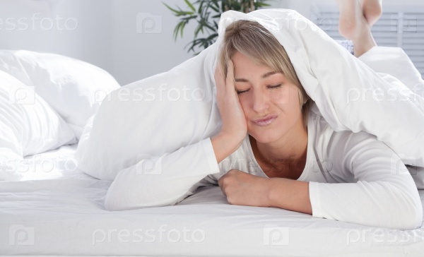 beautiful young woman in white bed in the morning, does not want to wake up. Not enough sleep.