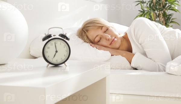 beautiful girl sleeping in her bed. clock on the nightstand. focus on face