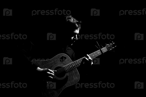 Male musician playing on acoustic guitar. Black and white photo.