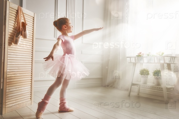 Cute little girl dreams of becoming a ballerina. Child girl in a pink tutu dancing in a room. Baby girl is studying ballet.