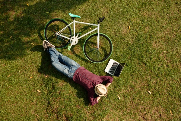 Man resting on the ground with laptop and bicycle next to him