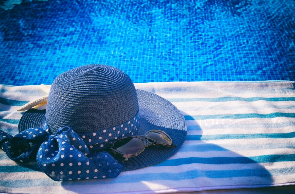 Towel and summer hat near water of pool, retro toned, stock photo