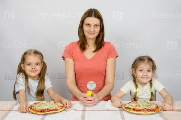 At the table sat my mother with a knife for pizza and two daughters to whom two pizzas, stock photo