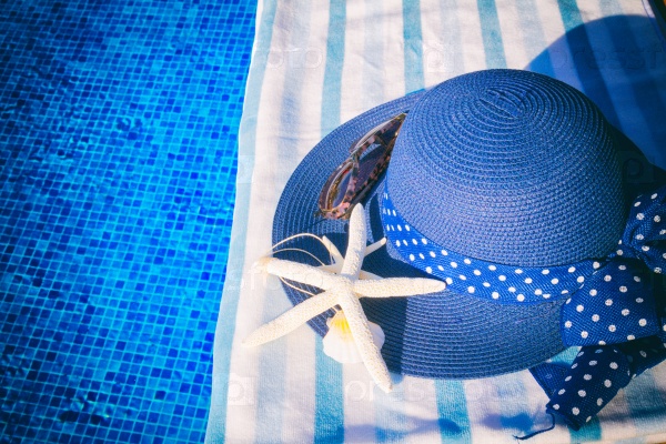 Towel and summer hat with seashells near water of pool, retro toned , stock photo