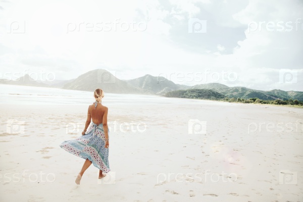 Woman wearing ethnic flying dress walking barefoot at the beach, Lombok, Indonesia, stock photo
