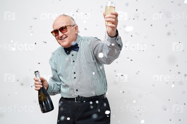 Happy senior man with bottle and flute of champagne looking at camera at party, stock photo