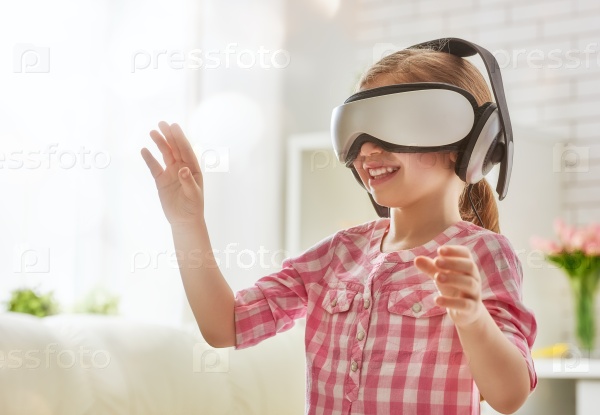 Cute little child girl playing game in virtual reality glasses.