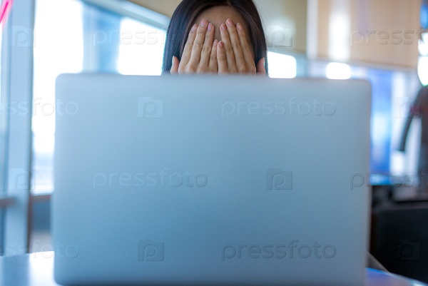 Person hidden behind the laptop surfing the internet, stock photo