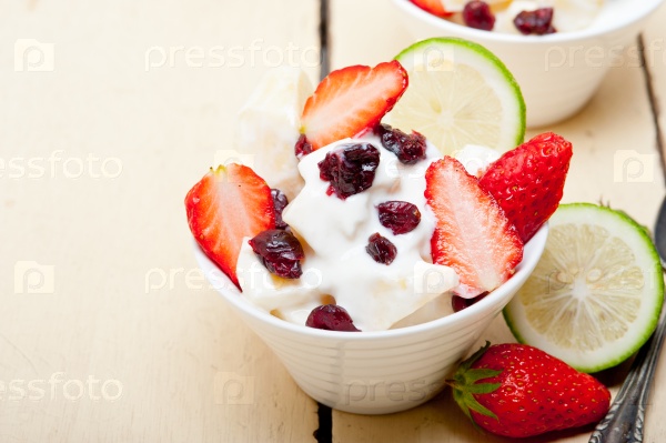 Fruit and yogurt salad healthy breakfast over white wood table, stock photo