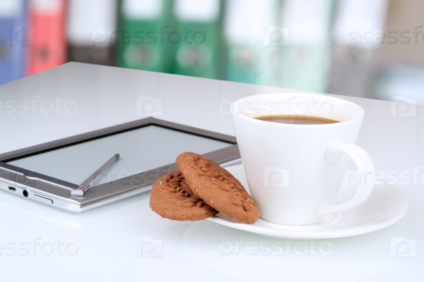 Close up image of cup of coffee with cookies. digital tablet on the table behind