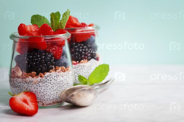Chia seeds vanilla pudding and berries on blue background - Healthy food, Diet, Detox, Clean Eating or Vegetarian concept, stock photo