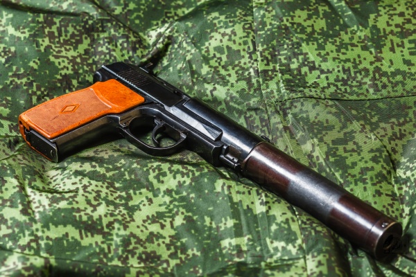 Weathered generic russian soviet semi-automatic 9mm silenced pistol on pixel camouflage background, stock photo