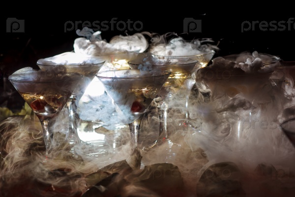 Drink in glasses with the effect of dry ice on black background, stock photo