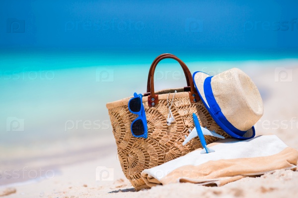 Beach consept - straw bag, hat, sunglasses and towel on white beach, stock photo